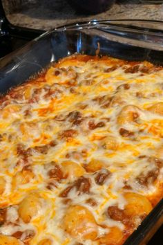 a casserole dish with meat and cheese in it sitting on a stove top