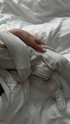 a person laying in bed with white sheets and polka doted blankets on top of them