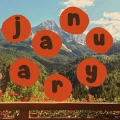 there are four orange circles that spell out the word may on a bench in front of mountains