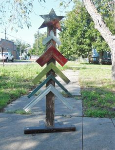 a wooden pole with many different colored arrows on it's side in front of a tree