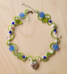 a green and blue beaded bracelet with a heart charm