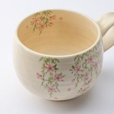 a white bowl with pink flowers on it and a spoon sticking out of the side