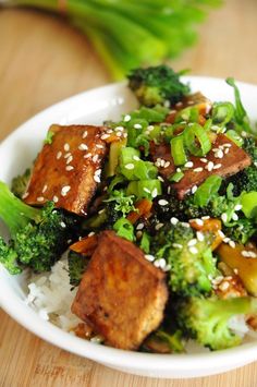 a white bowl filled with tofu and broccoli covered in sesame seeds on top of rice