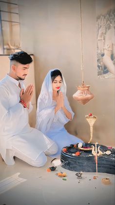 a man and woman kneeling in front of a cake