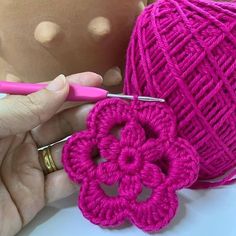 crochet flowers being worked on by someone using pink yarn to make them look like they are knitting