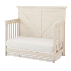 a white baby crib with a mattress and wooden slats on the bottom bed