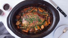 a pork roast in a crock pot with carrots and parsley