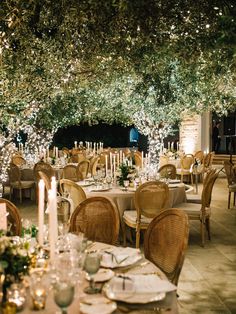 an outdoor dining area with tables, chairs and candles lit up at the end of each table