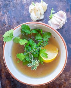 a bowl filled with soup next to garlic and lemon