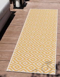 a yellow and white rug sitting on top of a wooden floor next to a lamp