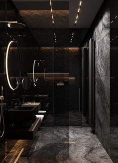 a bathroom with black walls and marble flooring is lit by recessed lights above the sinks