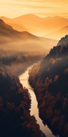 an aerial view of a river surrounded by trees and mountains in the background at sunset