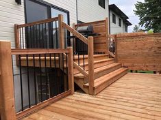 a wooden deck with stairs and railings next to a home's front door