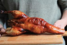 a person holding a piece of chicken on a cutting board