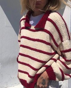 a woman wearing a red and white striped sweater is holding her hand in her pocket