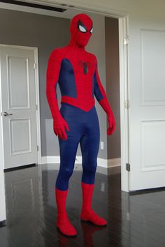 a man in a spiderman costume standing on a hard wood floor