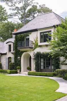 a large white house with lots of windows and bushes on the front lawn in front of it