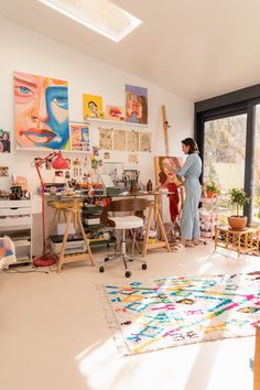 a woman is standing in an art studio looking at her work on the easel