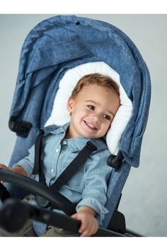 a young boy sitting in a stroller with a pillow on top of his head