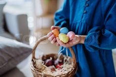 a woman holding two small eggs in a basket