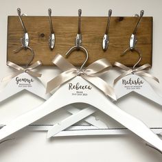 three wooden hangers with ribbons on them are attached to a coat rack that holds five pairs of clothes