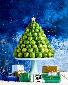 a christmas tree made out of brussels sprouts and wrapped presents on a platter