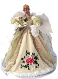 an angel figurine holding a bouquet of flowers and wearing a white dress with gold trimmings