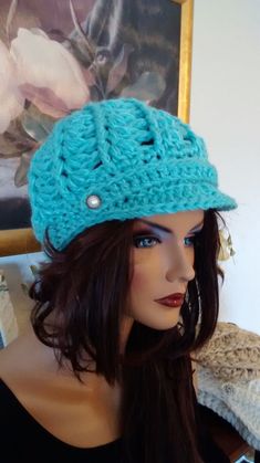 a mannequin head wearing a blue crochet hat with buttons on it