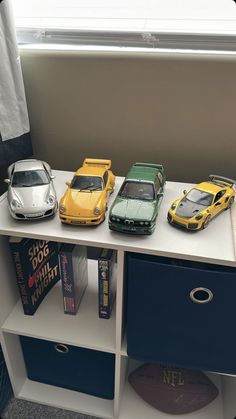 three toy cars are sitting on top of a book shelf