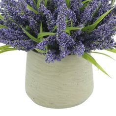 a white vase filled with purple flowers on top of a table