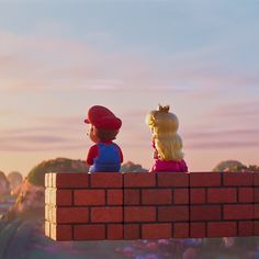 two little kids sitting on top of a brick wall looking out at the city below