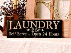 a wooden sign that says laundry self serve open 24 hours on top of a table