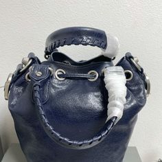 Balenciaga 's popular 'Le Cagole' series is a modern interpretation of its 'City' handbags - reshaped into a bucket bag design to inject a new soul into it. The large size adds two round top handles, combining classic and Modern trends are perfectly integrated. On the basis of retaining the original DNA of the motorcycle bag's flat rivets, delicate buckles and tassel zippers, it adds adjustable woven shoulder straps and a cute and playful heart-shaped mirror, which perfectly softens the neutral New Soul, Shaped Mirror, Motorcycle Bag, Lv Purse, Lv Shoes, Gucci Bamboo, Lv Belt, Lv Handbags, Lv Wallet