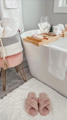 a white bath tub sitting next to a wooden tray filled with towels and other items