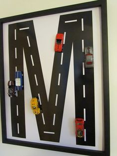 a black frame with cars and trucks on the letter m made out of cardboard paper