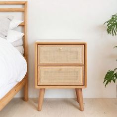 a bedroom with a bed, nightstand and plant on the side table in front of it