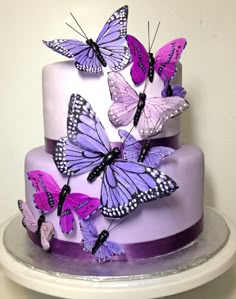 a three tiered cake with purple butterflies on it