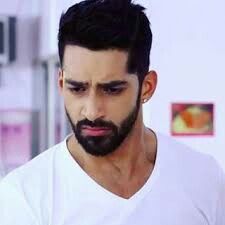 a man with a beard looking down at his cell phone while wearing a white t - shirt