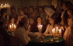 a group of people sitting around a table with candles