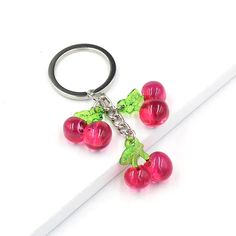 a key chain with three cherries hanging from it's end on a white surface