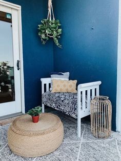 a white bench sitting on top of a floor next to a blue wall and potted plant