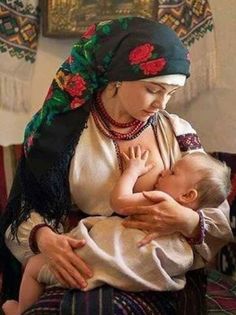 a woman holding a baby in her arms while wearing a head scarf and necklaces