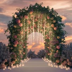 an archway decorated with candles and flowers in the middle of a snow covered field at sunset