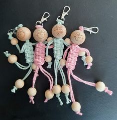 three little wooden dolls are hanging on the wall with their faces drawn in crochet