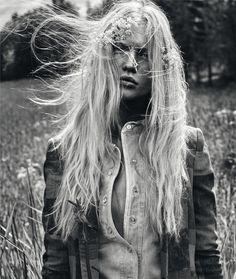 a woman with long hair standing in a field