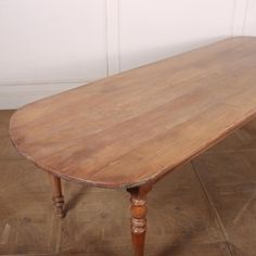 an old wooden table sitting on top of a hard wood floor next to a white wall