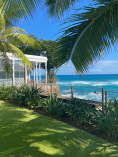 a gazebo sitting on the side of a lush green field next to the ocean