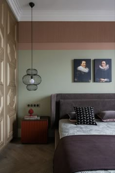 a bedroom with two paintings hanging on the wall and a bed in front of it