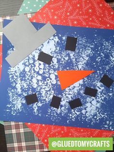 a snowman made out of construction paper on top of a plaid tablecloth with black squares