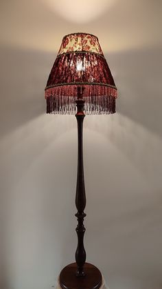 a lamp that is on top of a wooden base and has a red shade over it